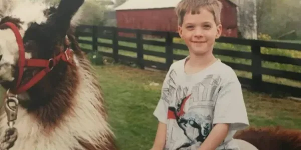 A childhood photo of Dr. Harlan beside a llama