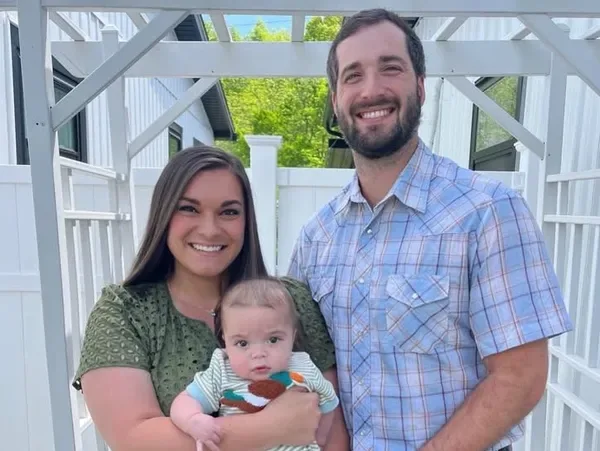 Dr. Matthew Harlan with his wife Bailee and their son under a white arbor