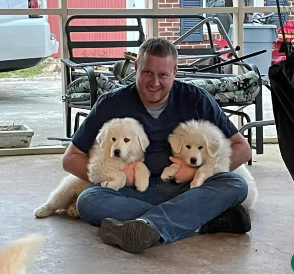 Dr. Jacob Harris sitting on a porch holding two white puppies