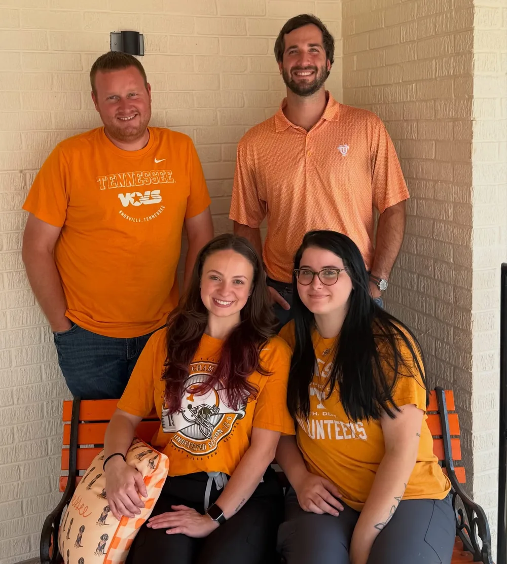 Four members of the team in Tennessee orange on the clinic porch bench